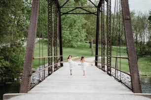 Duas jovens estão dançando em uma ponte
