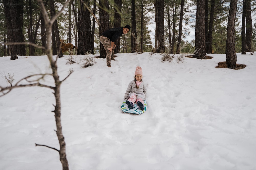 uma criança pequena deitada na neve em uma prancha de snowboard