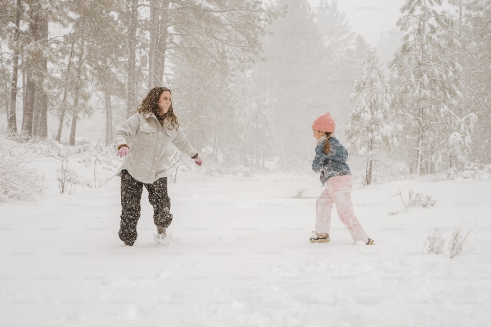 a woman and a child playing in the snow