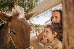 uma mulher e uma menina acariciando um cavalo