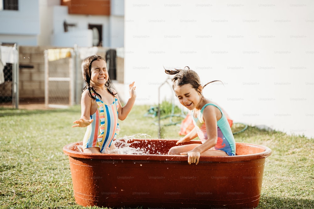 zwei kleine Mädchen, die in einer Wanne mit Wasser spielen