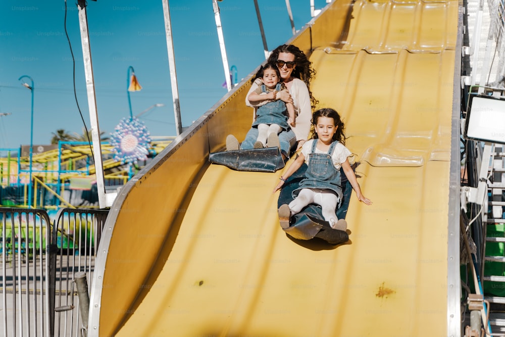 two young girls sliding down a yellow slide