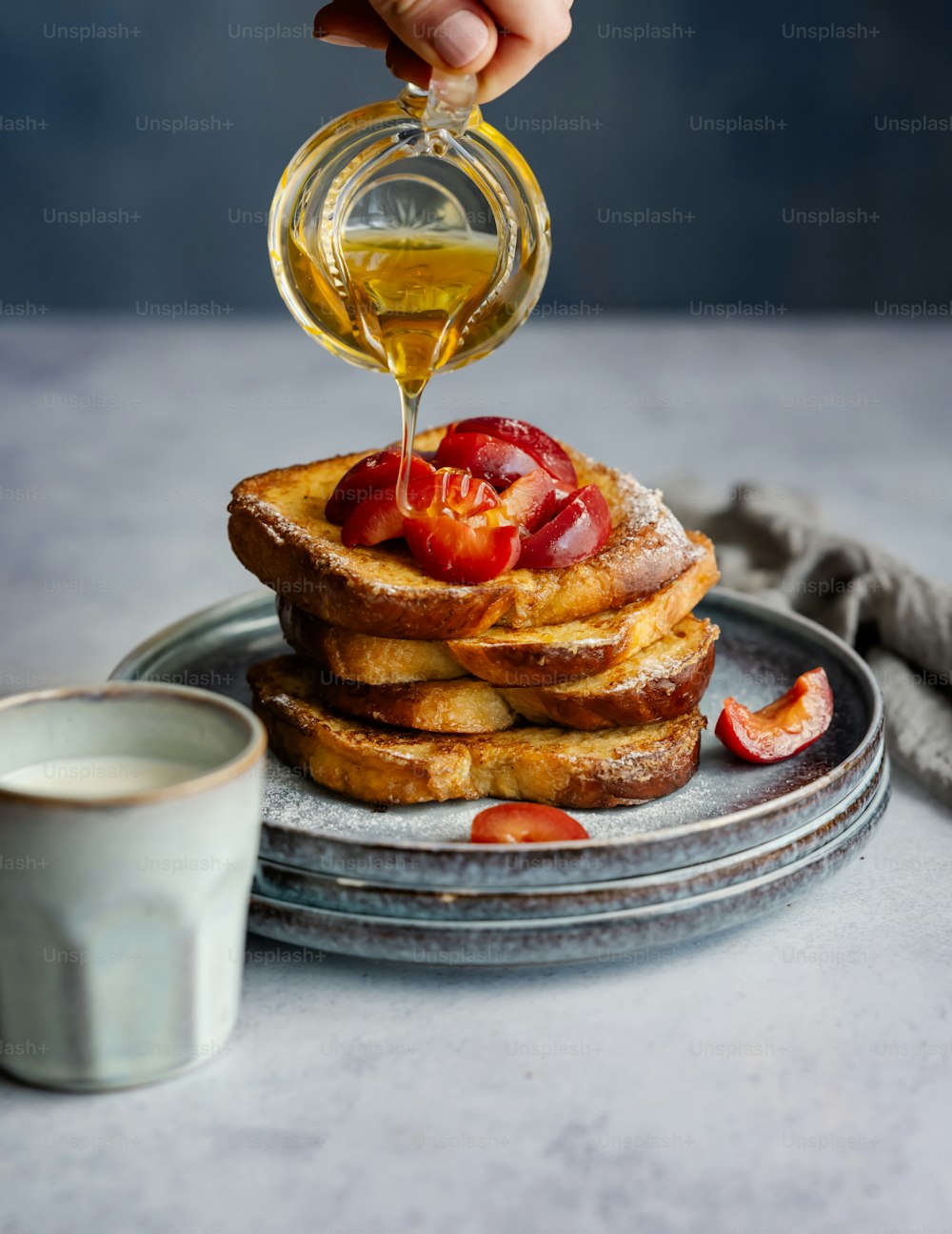 a stack of french toast with syrup being poured on top