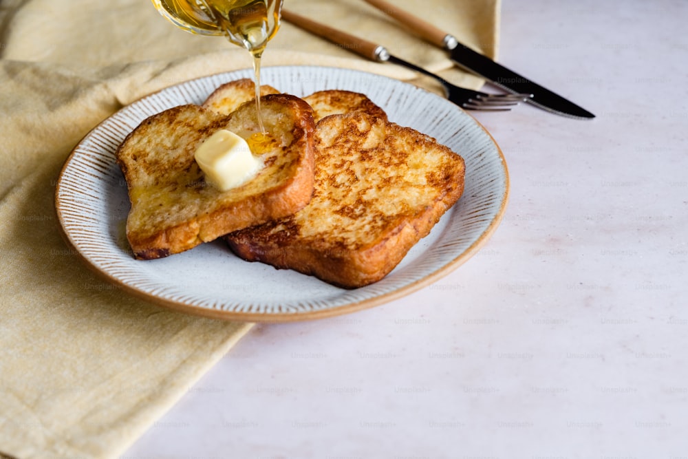 two pieces of toast on a plate with butter and a glass of wine