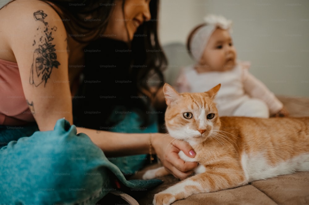 a woman holding a baby and a cat