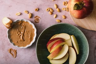 a bowl of peanut butter next to a bowl of apples