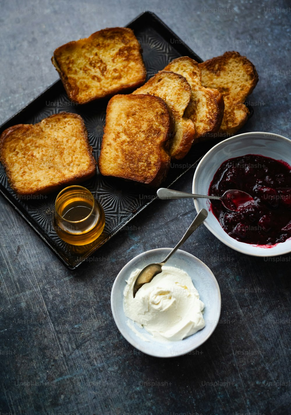a tray of food with bread, jam, and butter on it