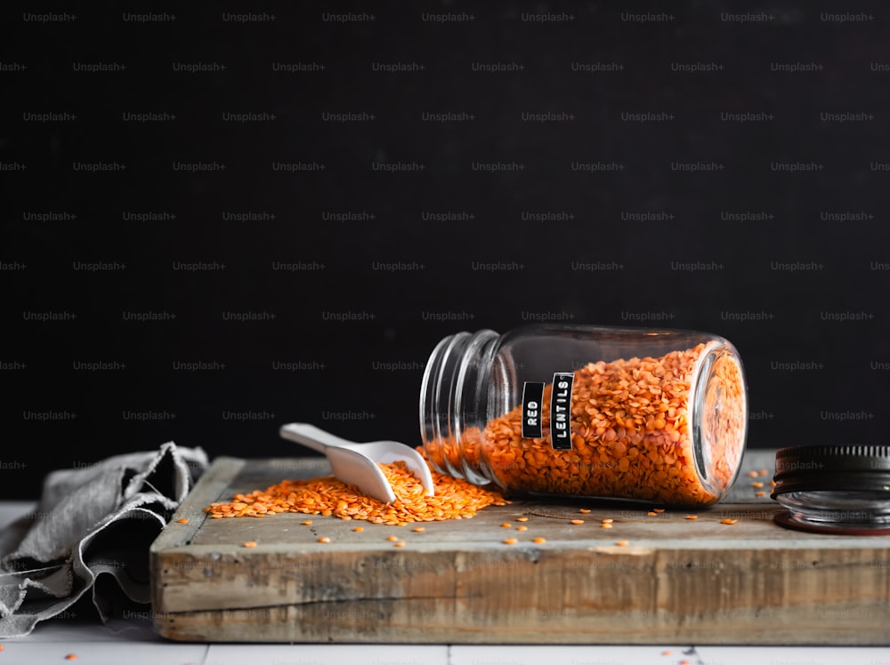 a jar of red lentils on a cutting board