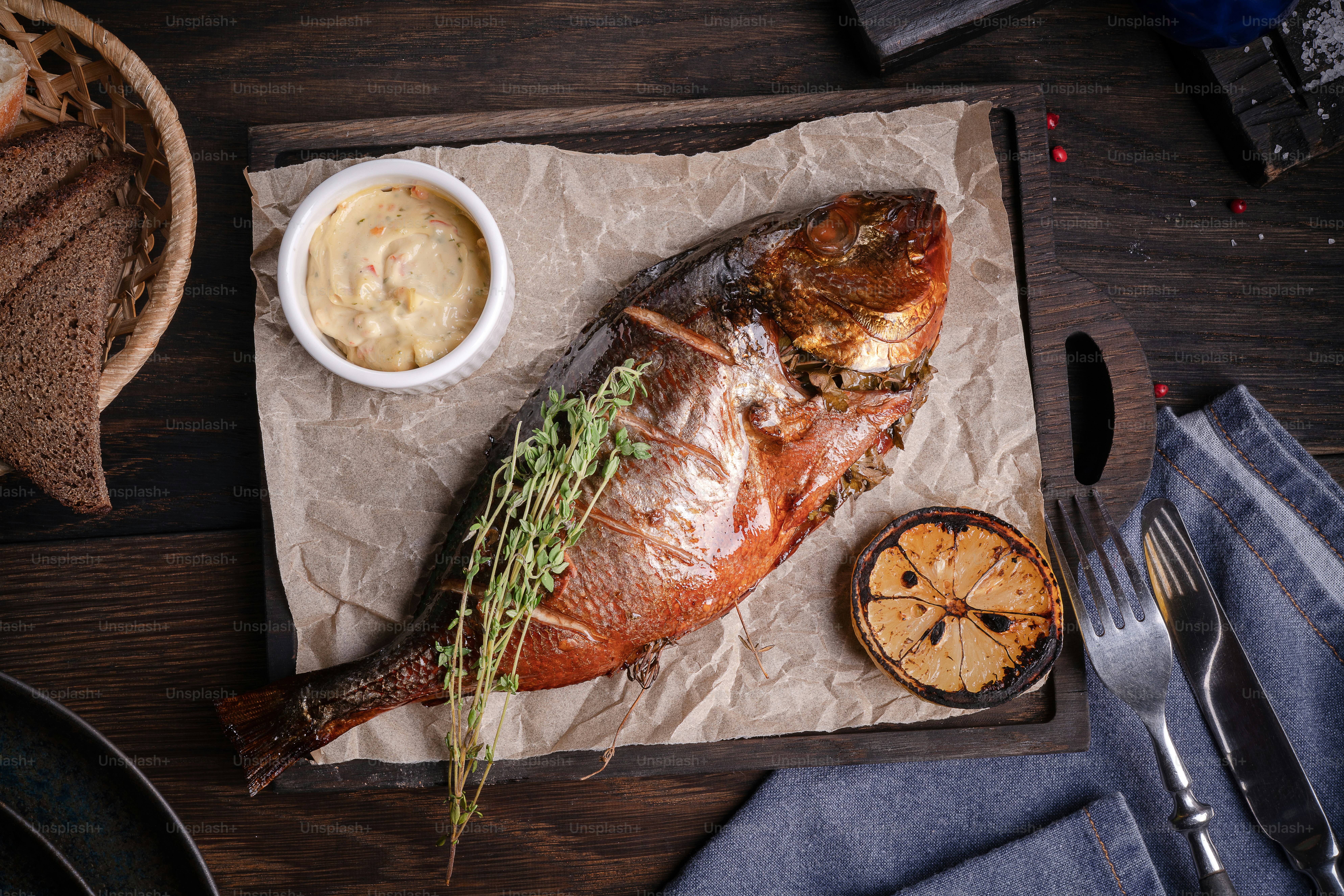 a fish on a tray next to a bowl of sauce