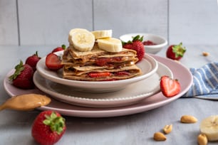 a stack of pancakes topped with bananas and strawberries