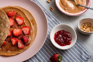 a plate topped with pancakes covered in peanut butter and strawberries