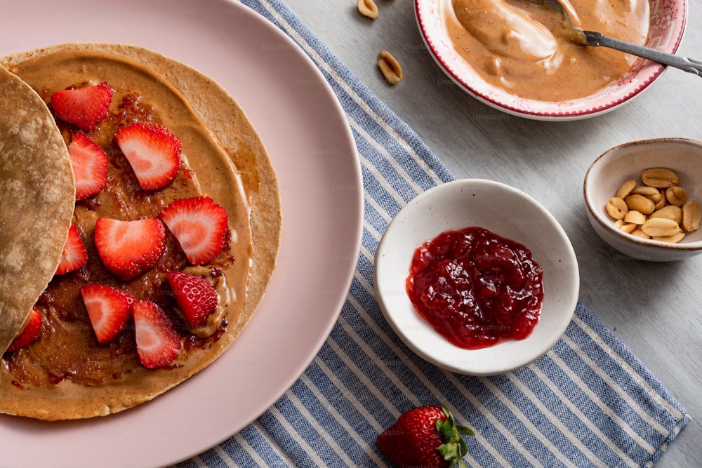 a plate topped with pancakes covered in peanut butter and strawberries