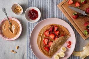 a plate topped with a piece of fruit next to a bowl of peanut butter and