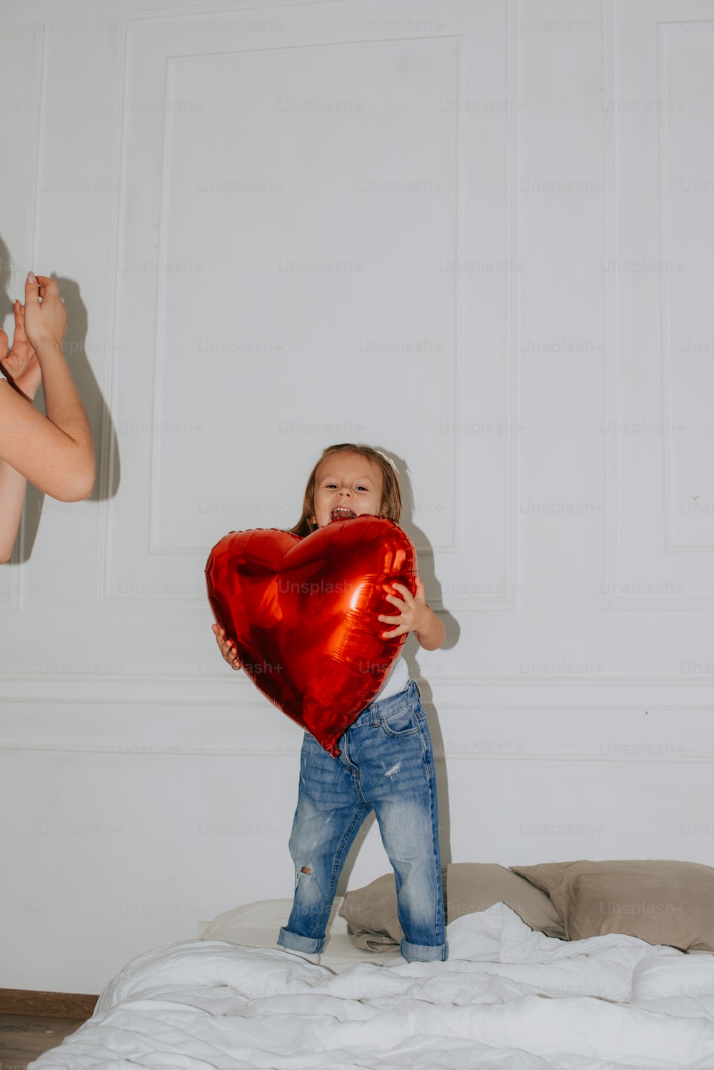 a little girl holding a heart shaped balloon