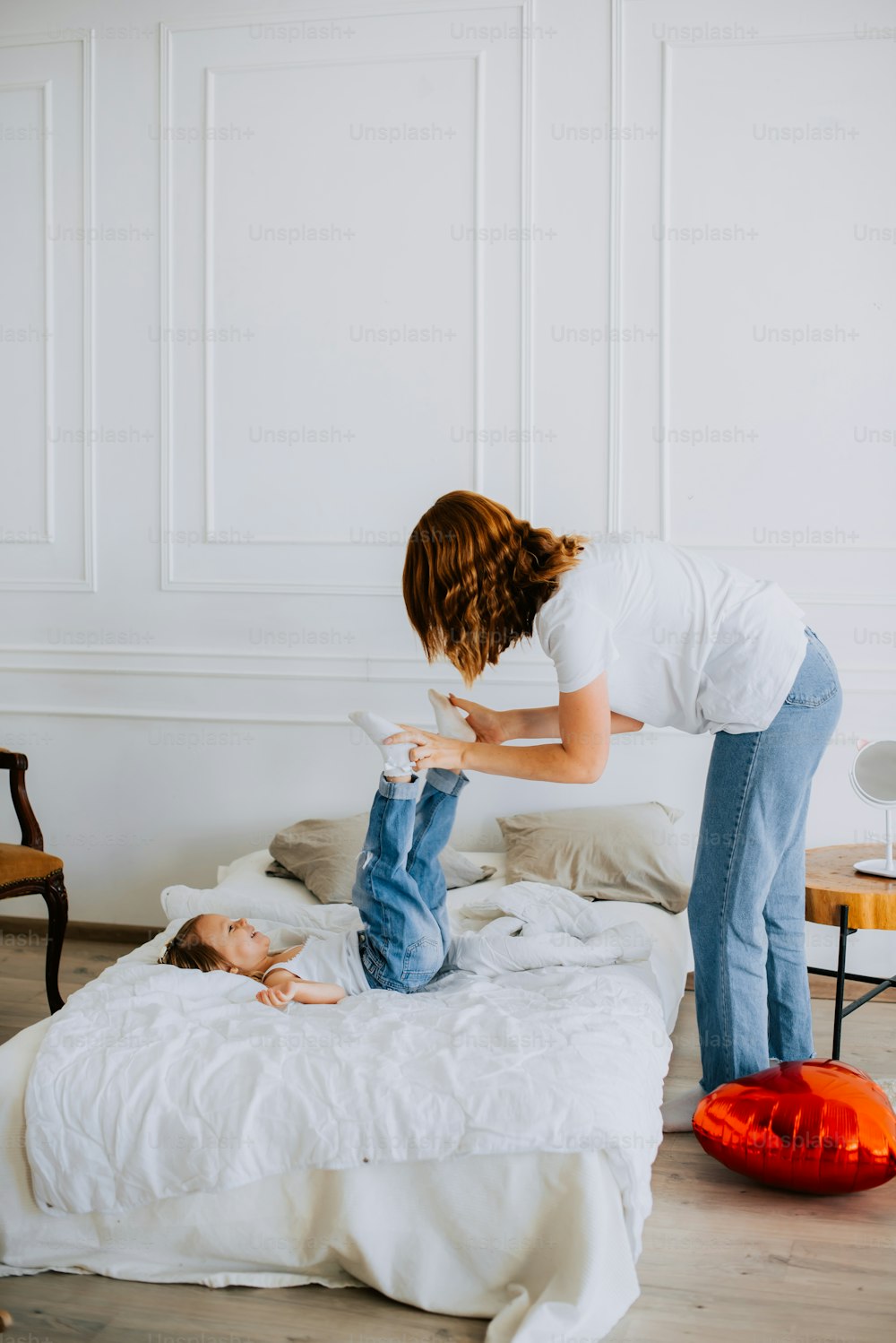 a woman in white shirt and jeans standing over a bed