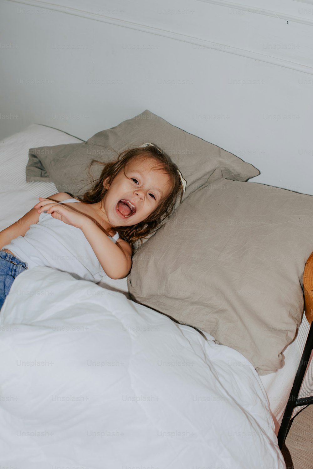 a little girl laying in a bed with a pillow