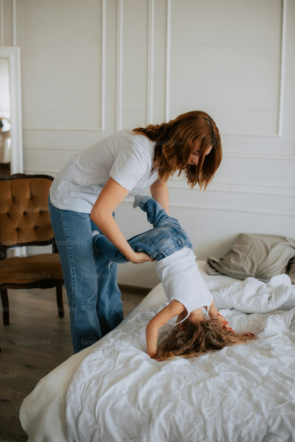 a woman standing over another woman laying on a bed