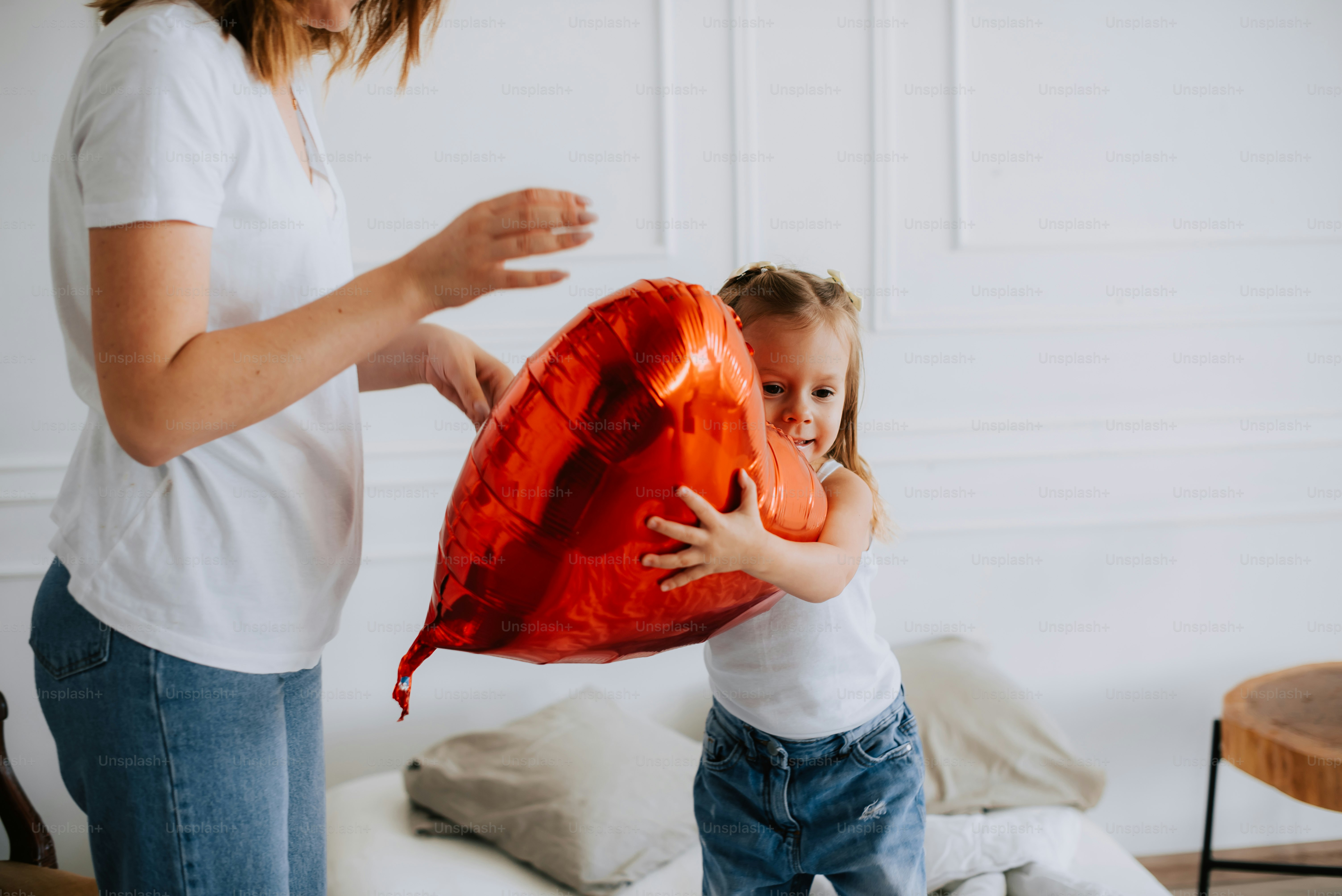 Seorang gadis kecil memegang balon berbentuk hati merah