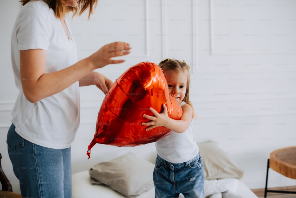 una niña sosteniendo un globo rojo en forma de corazón