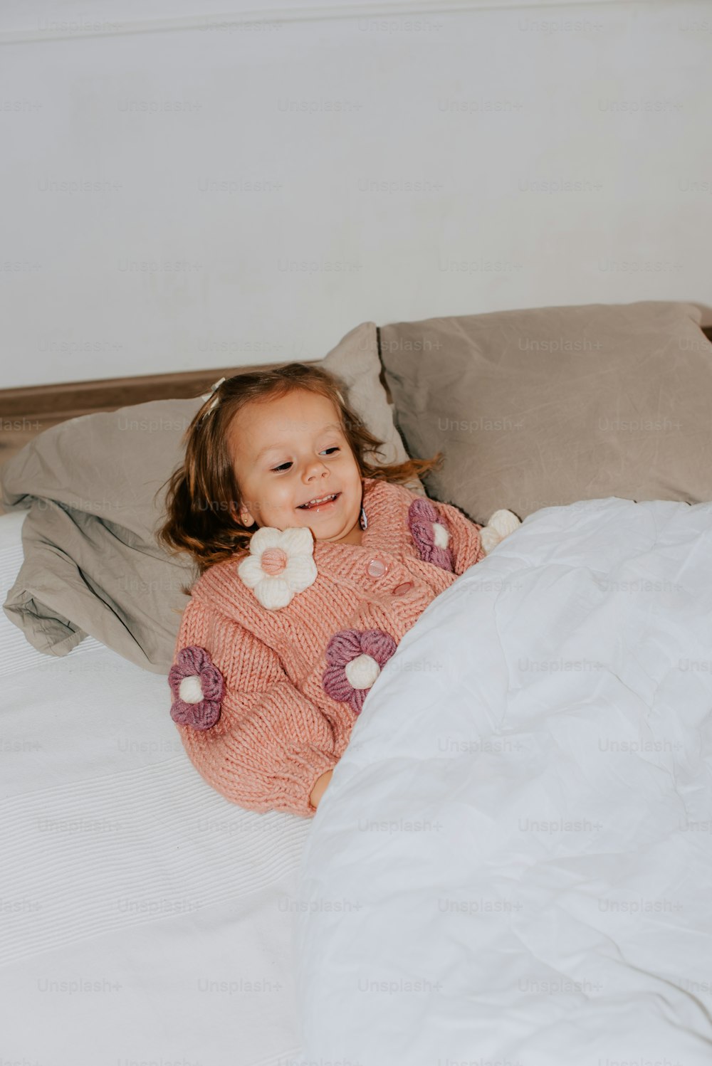 une petite fille qui est couchée sur un lit