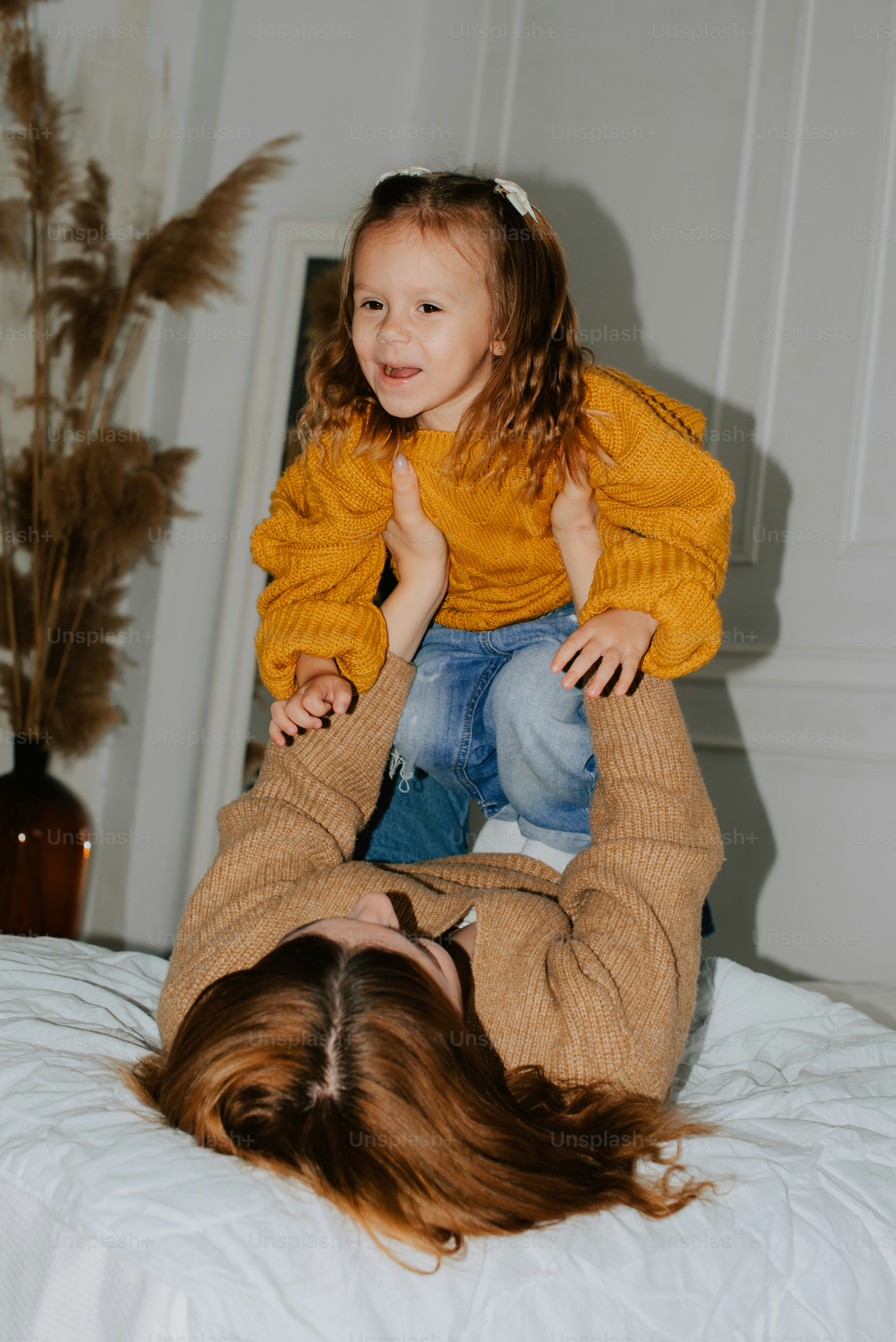 a woman holding a little girl on top of a bed