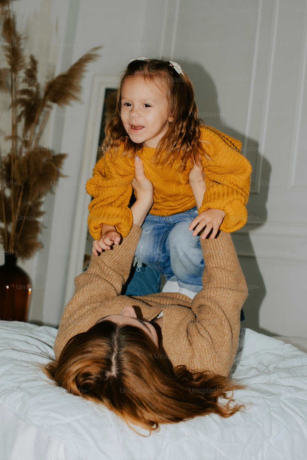 a woman holding a little girl on top of a bed