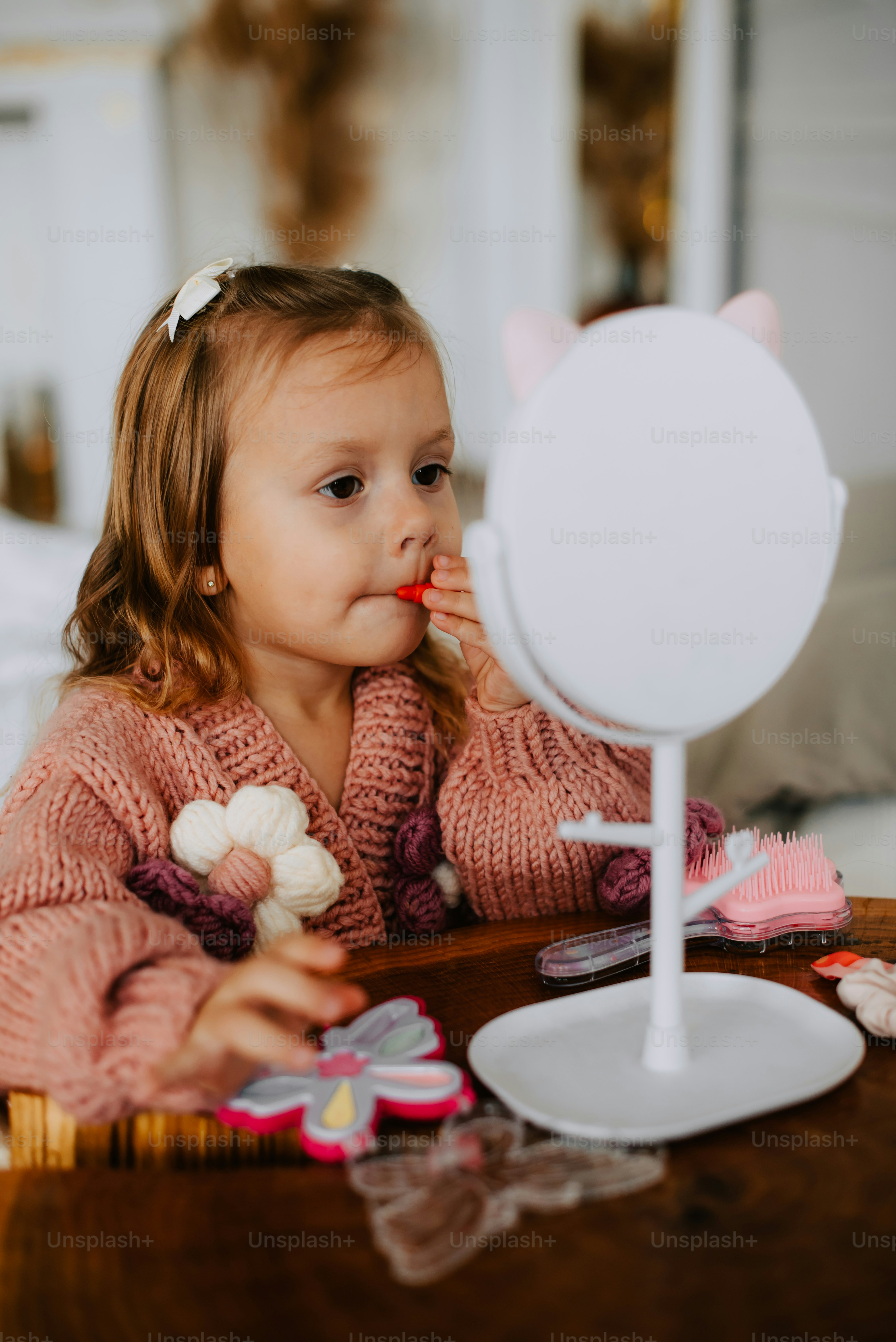ein kleines Mädchen sitzt an einem Tisch mit einem Spiegel