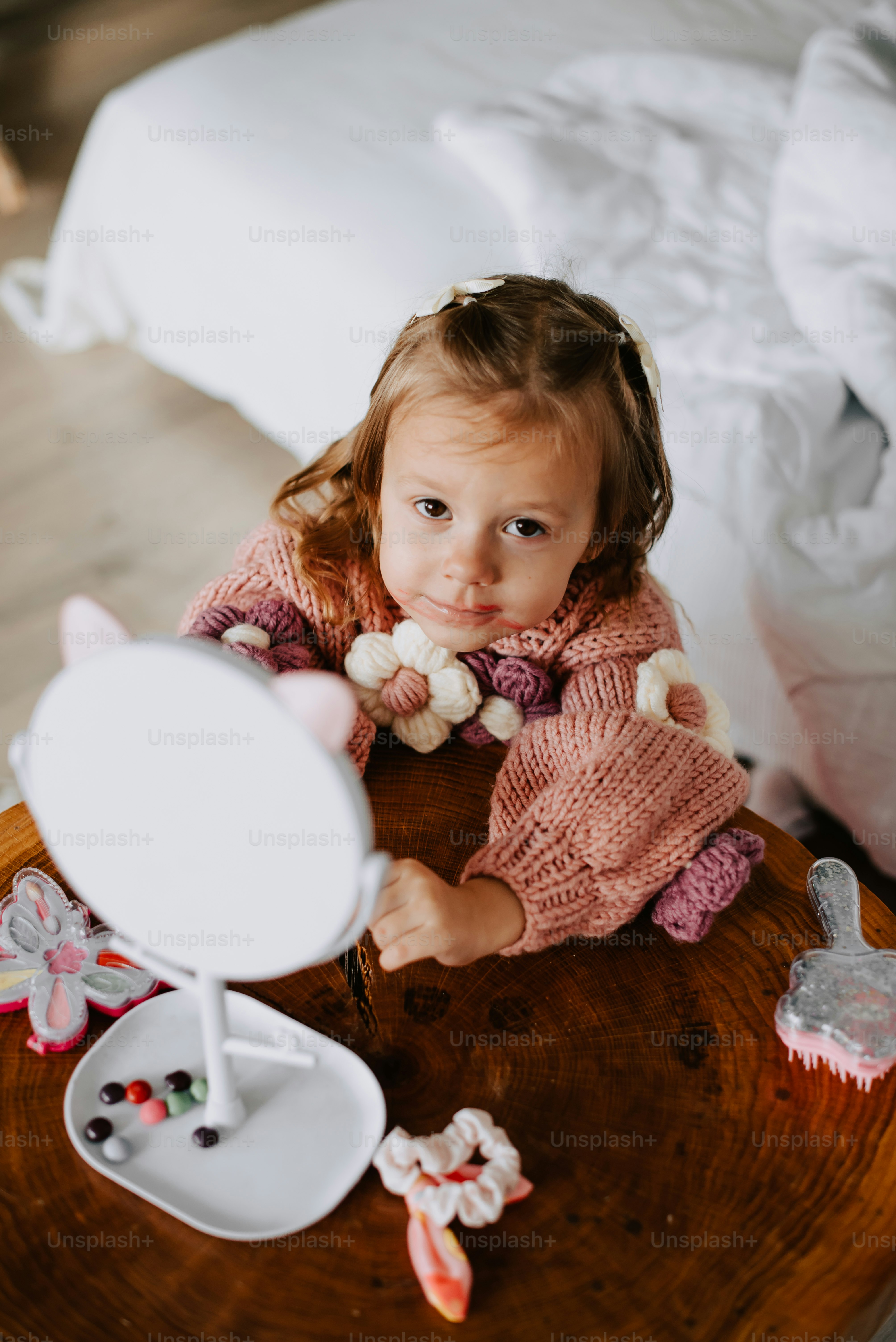 a little girl sitting at a table with a mirror