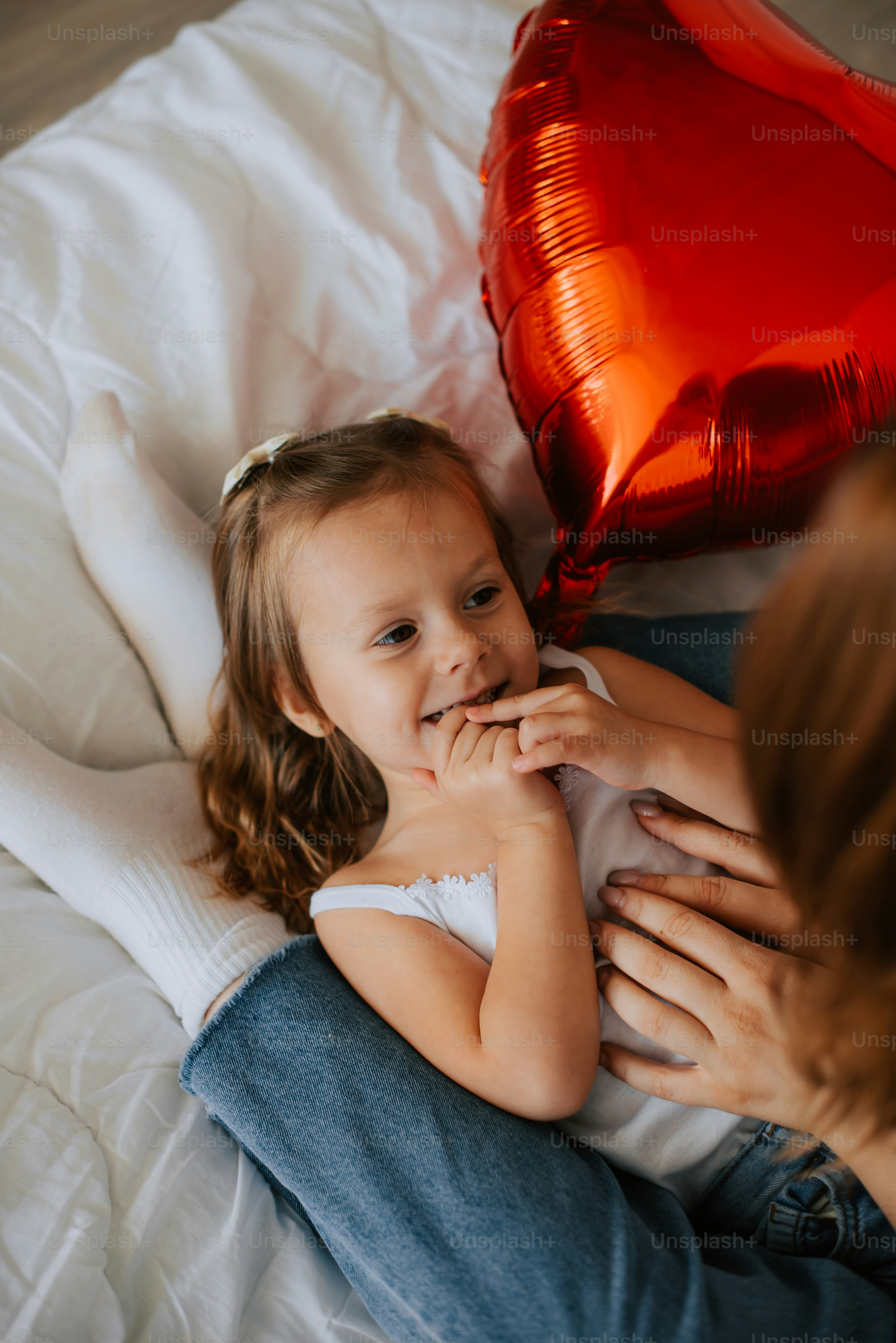 une petite fille allongée sur un lit à côté d’une femme