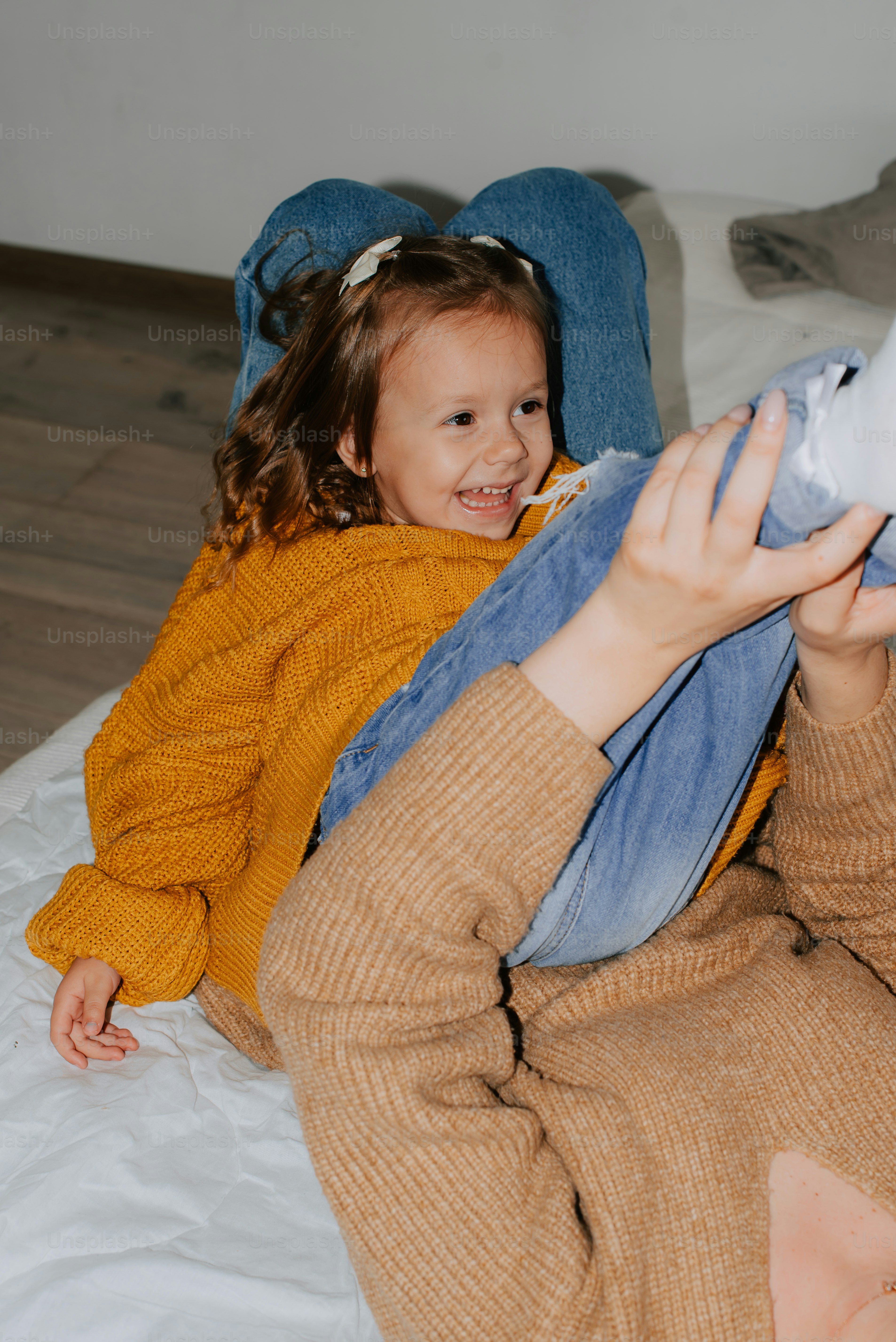 a little girl sitting on a bed holding a stuffed animal