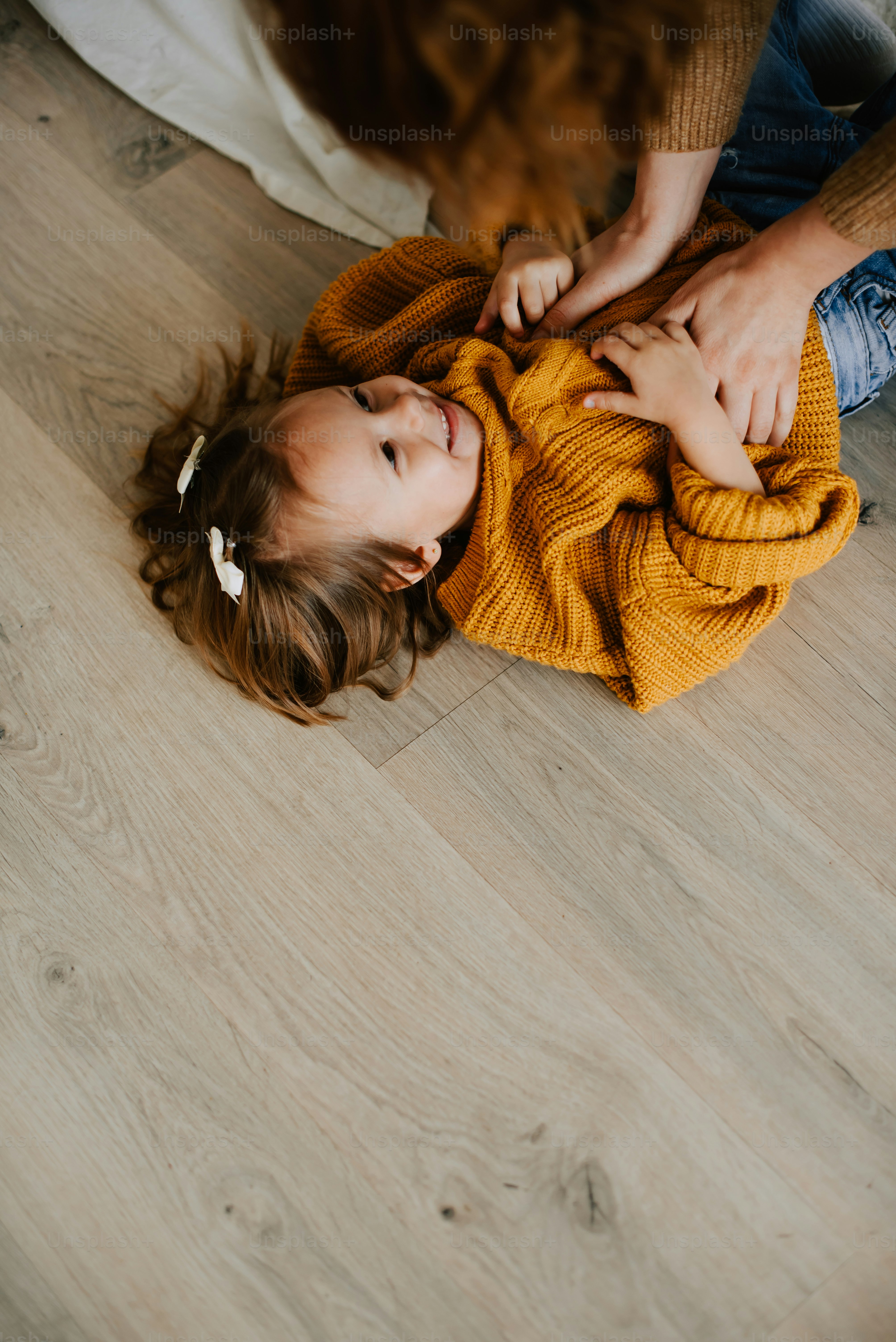 a little girl laying on the floor with her mother