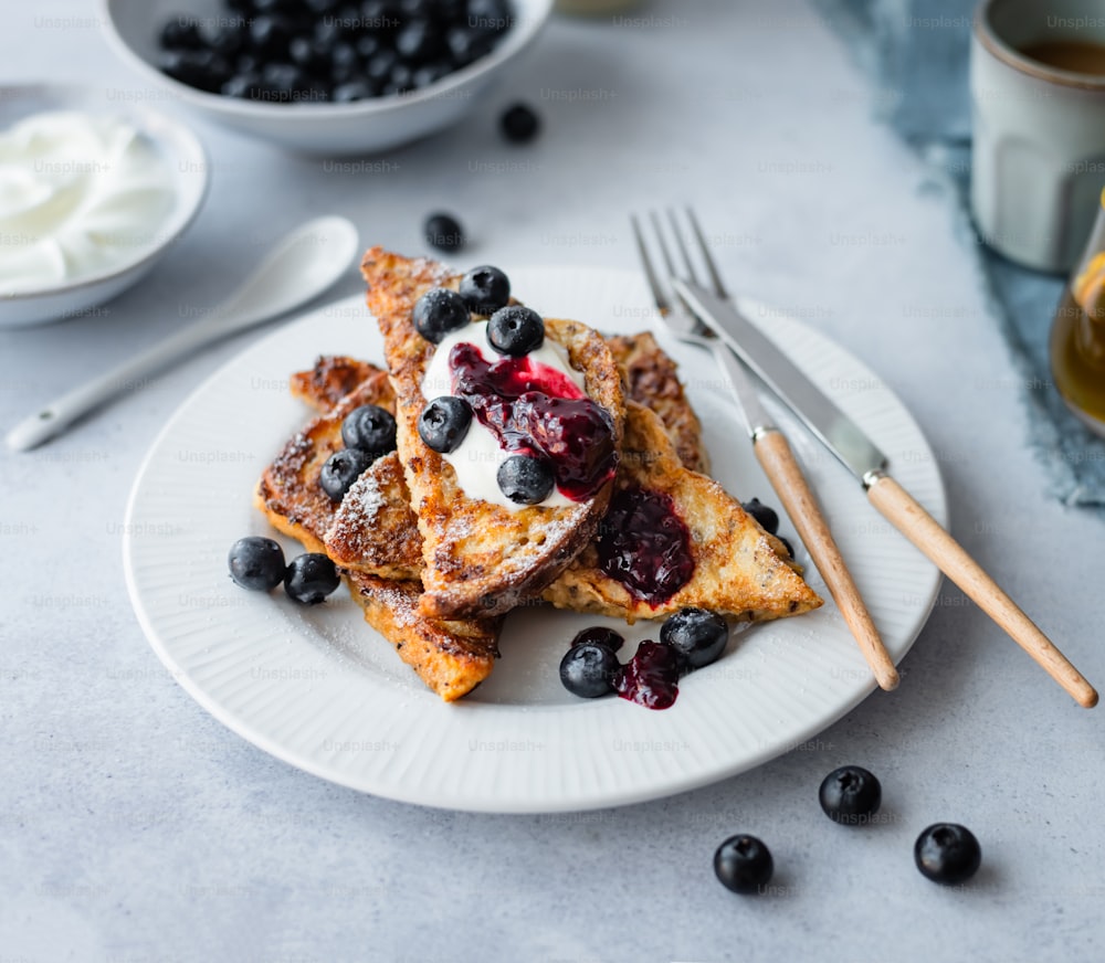 a white plate topped with french toast and blueberries