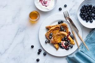 Ein weißer Teller mit French Toast und Blaubeeren