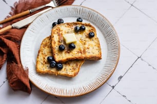 two pieces of toast with blueberries and butter on a plate