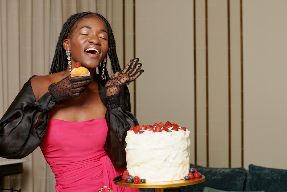 a woman in a pink dress is eating a cake