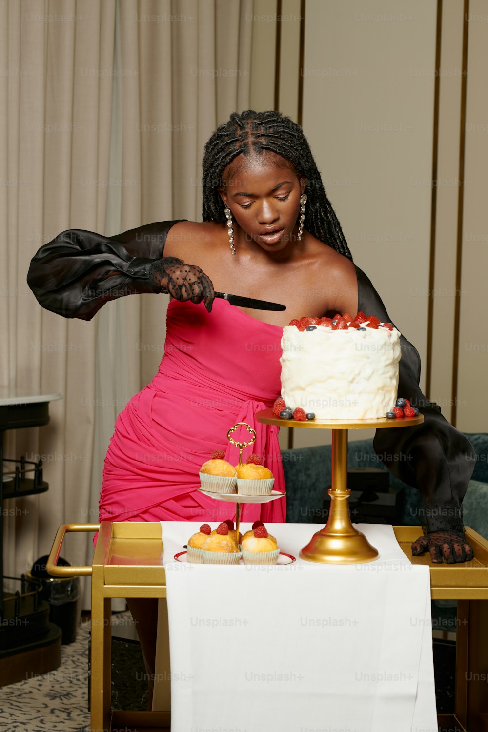 a woman in a pink dress cutting a cake