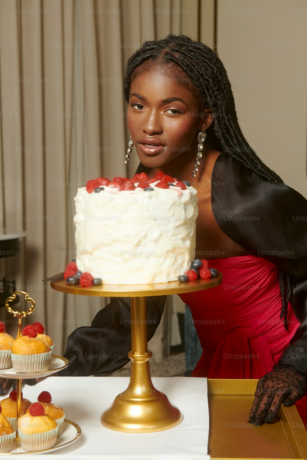 a woman in a red dress standing next to a cake