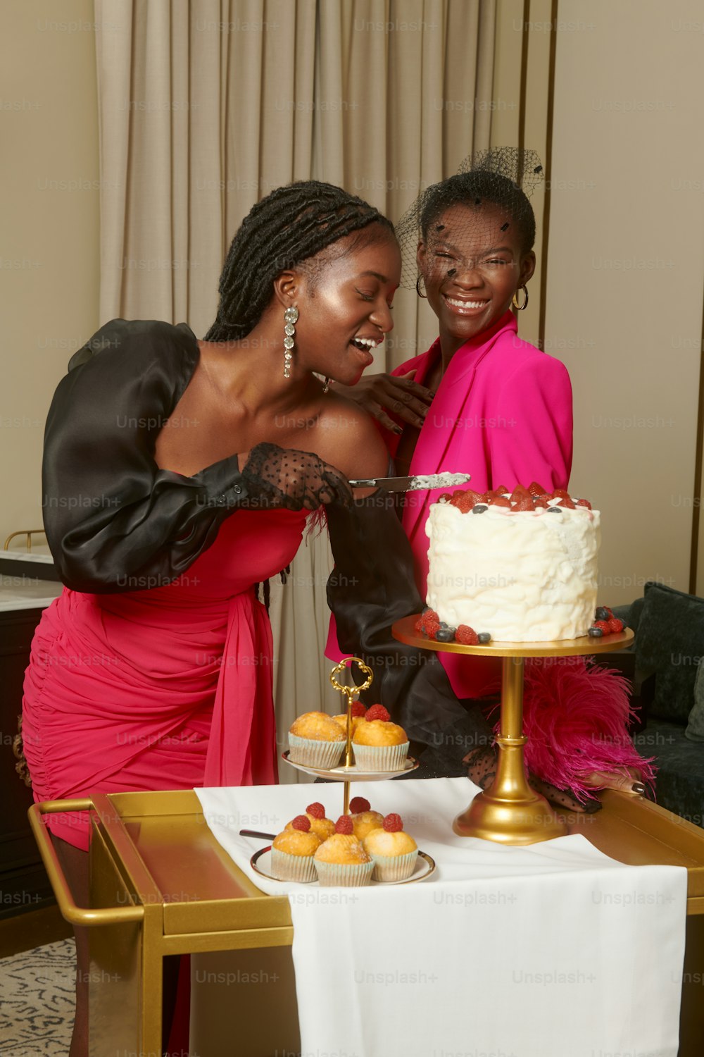 a couple of women standing next to each other in front of a cake