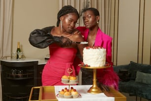a couple of women standing next to a cake