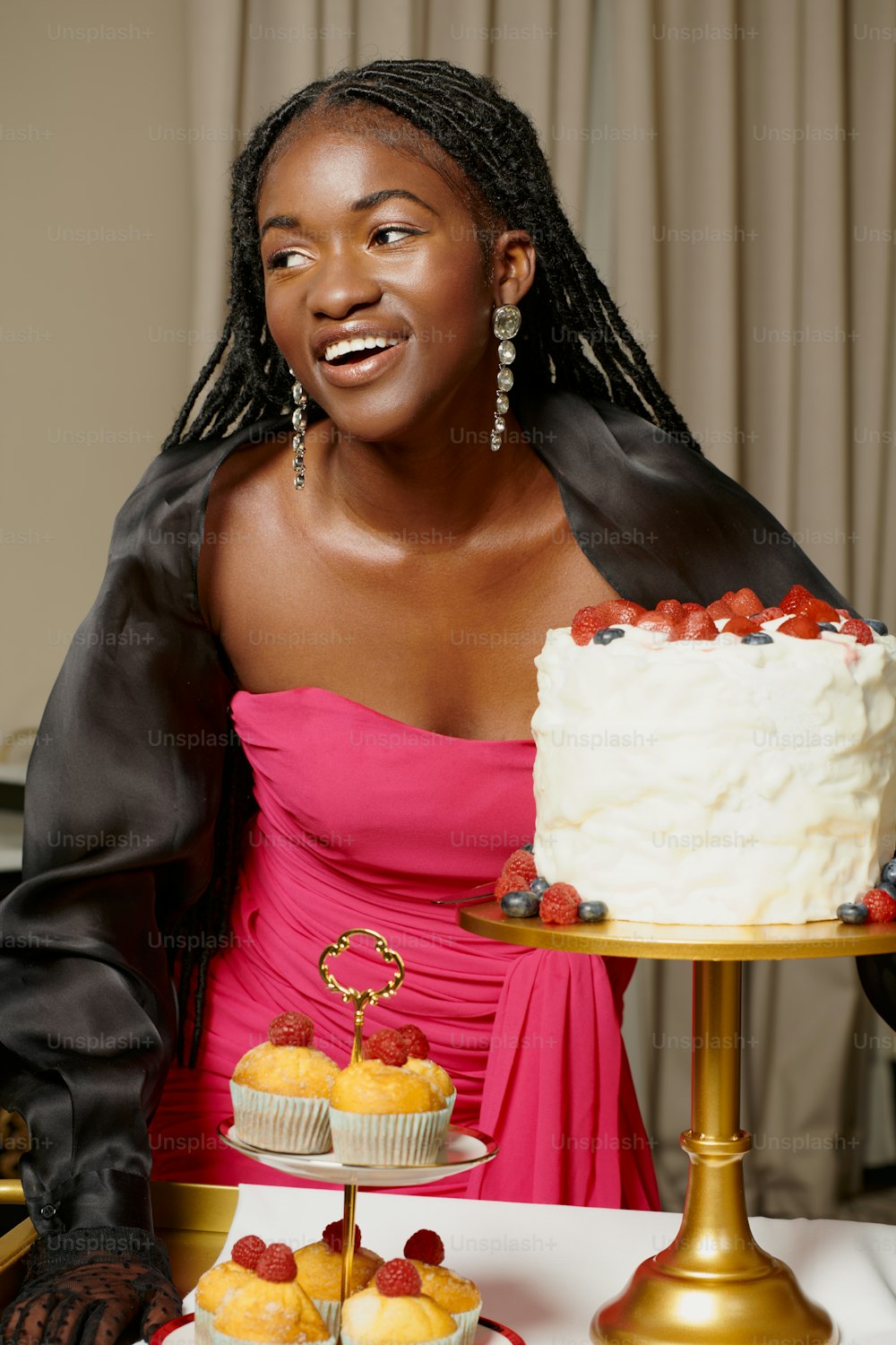 a woman in a pink dress standing in front of a cake