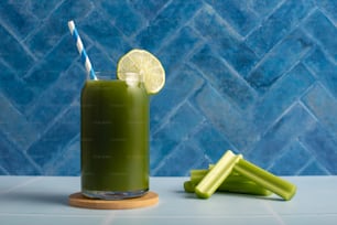 a green smoothie with a blue and white striped straw