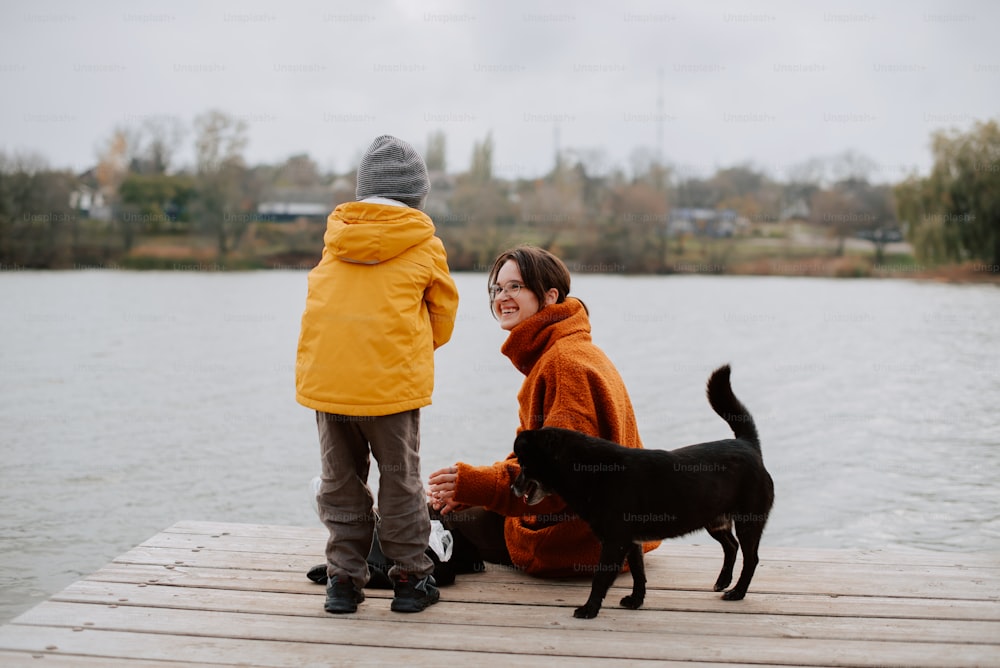 a woman and a child on a dock with a dog