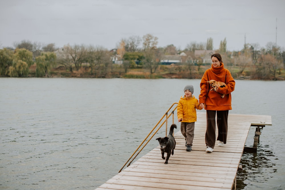 a woman and child walking on a dock with a dog