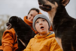 a young boy in a yellow jacket and a black dog