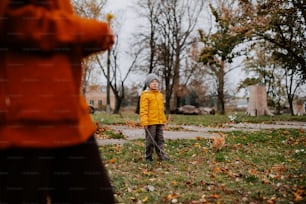 a little boy in a yellow jacket standing in the grass