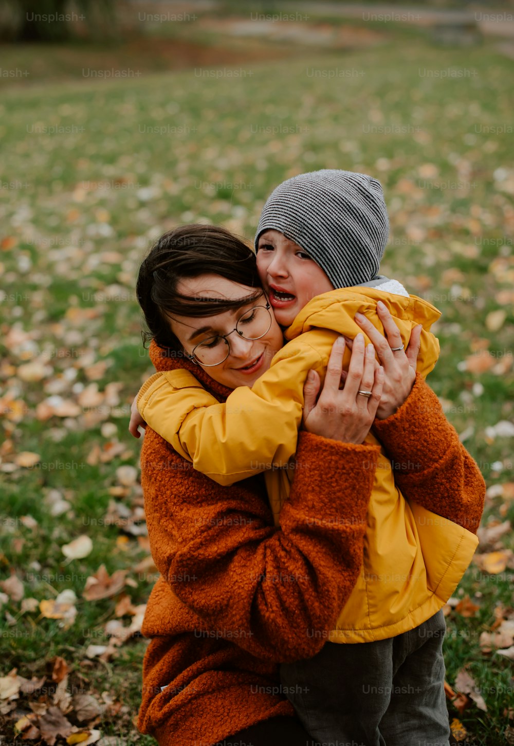 two women hugging each other in a field of leaves