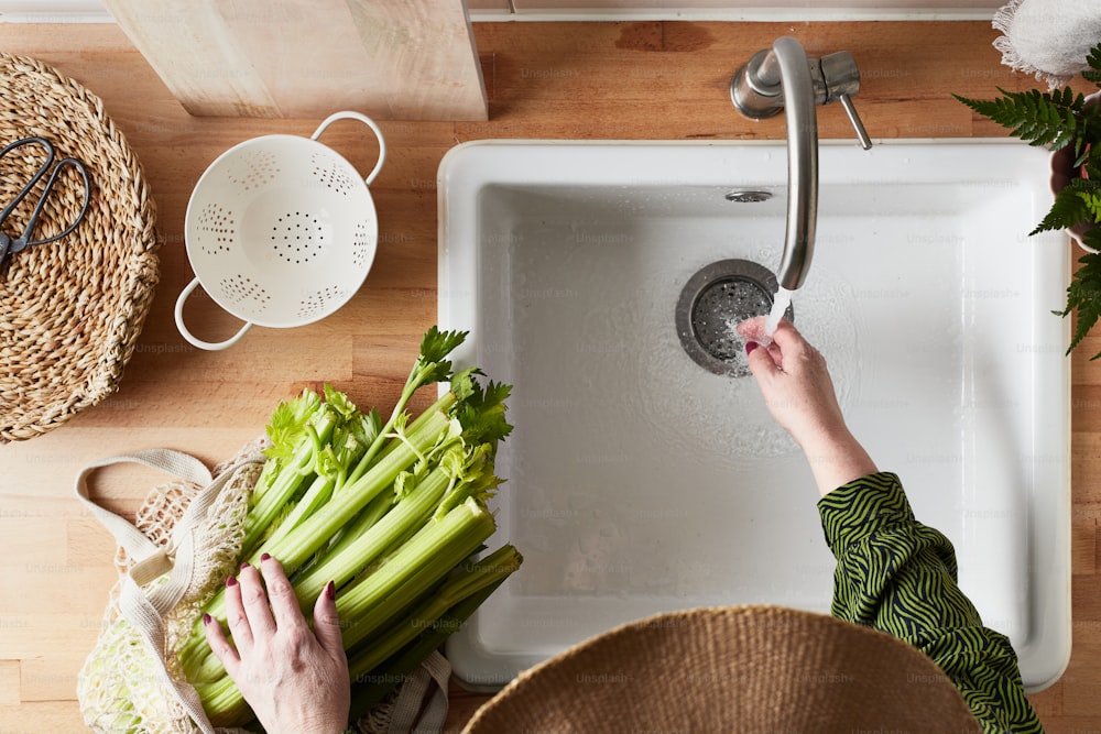 a person washing vegetables in a kitchen sink