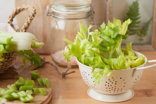 ein weißes Sieb gefüllt mit Salat auf einem Holztisch