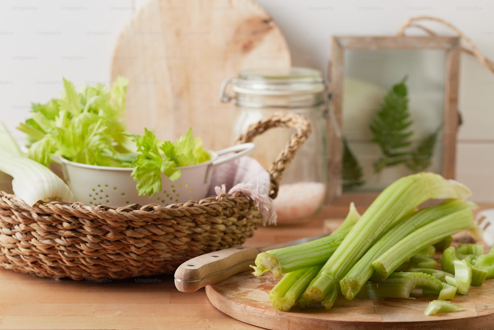 a wooden cutting board topped with celery next to a bowl of lettu