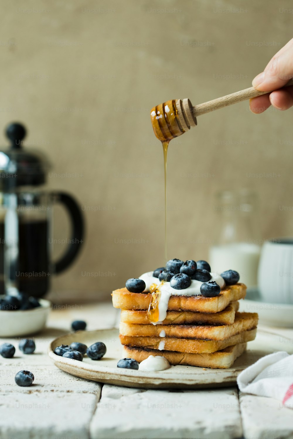 a stack of pancakes with blueberries and syrup being drizzled with honey